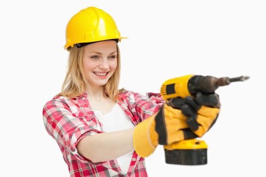 Joyful woman using an electric screwdriver against white background