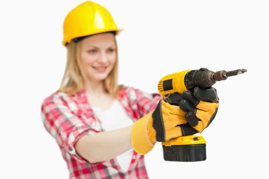 Cheerful woman using an electric screwdriver against white background