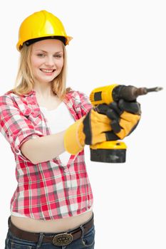 Woman using an electric screwdriver while smiling against white background