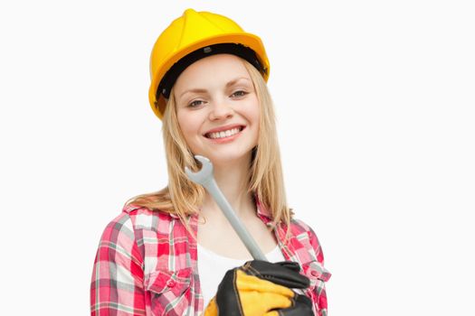 Woman holding a wrench while smiling against white background