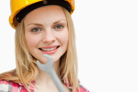 Close up of a woman holding a wrench against white background