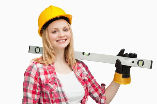 Smiling woman holding a spirit level against white background