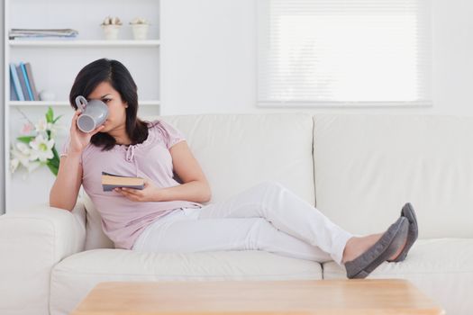 Drinking woman lying on a couch in a living room