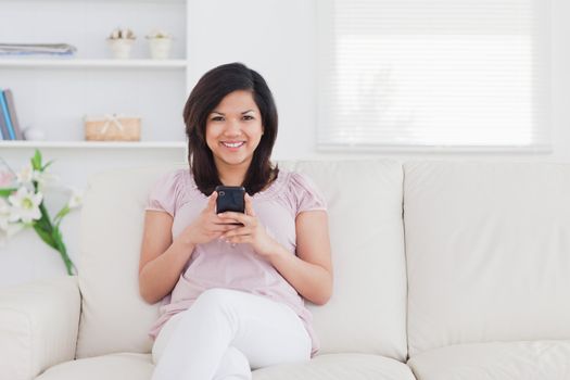 Woman sitting on a sofa while holding a phone