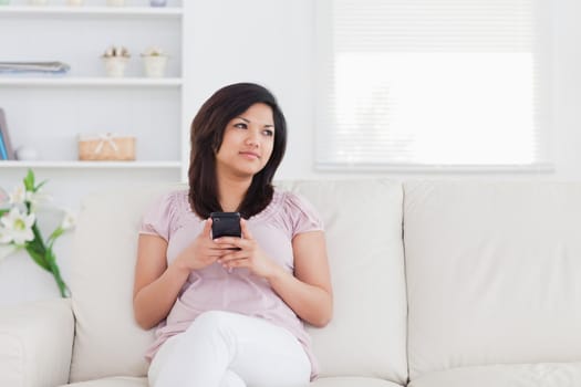 Woman sitting on a sofa and holding a phone in a living room