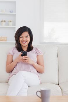 Woman smiling and holding a phone in a living room