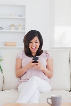 Woman surprised while looking at a phone in a living room