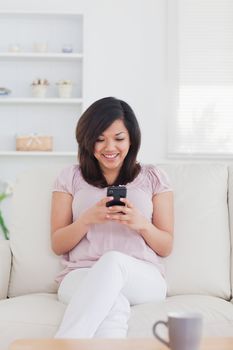 Woman smiling while holding a phone in a living room