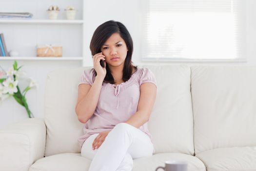 Woman phoning while she is sitting on a couch in a living room