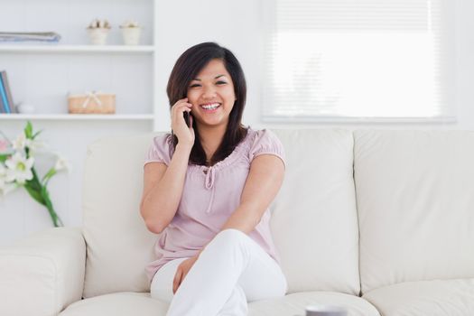 laughing woman holding a phone and sitting on a couch