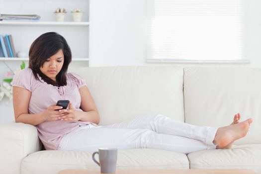 Woman lying on a couch while holding a phone in a living room