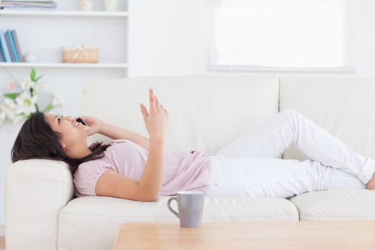 Woman relaxing on a sofa while phoning in a living room