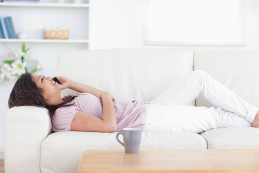 Woman relaxing as she holds a phone in a living room