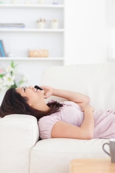 Woman resting on a sofa while phoning in a living room