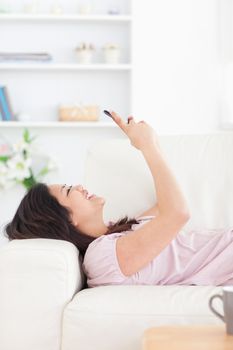 Woman laughing while resting on a couch and looking at a phone in a living room