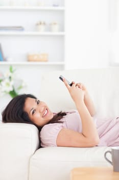 Woman resting on a couch while holding a phone in a living room