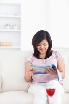 Woman sitting on a sofa while reading a magazine in a living room