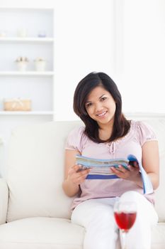 Woman holding a magazine and sitting on a couch in a living room