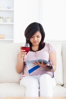 Woman sits on a couch and holds a magazine in a living room