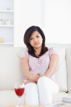 Woman sitting on a couch holding a television remote in a living room