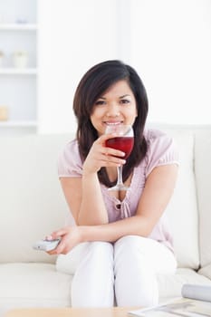Woman smiling and holding a glass of red wine in a living room