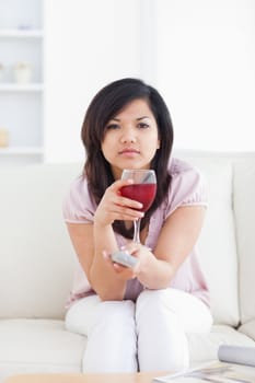 Woman sitting on a couch while holding a glass of red wine in a living room