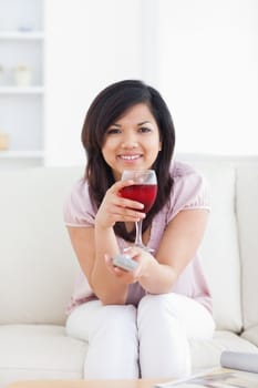 Woman holding a television remote while holding a glass of red wine in a living room