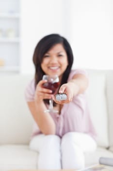 Woman drinking a glass of wine while holding a television remote in a living room