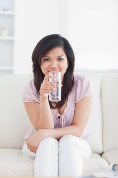 Woman drinking water while sitting in a couch in a living room