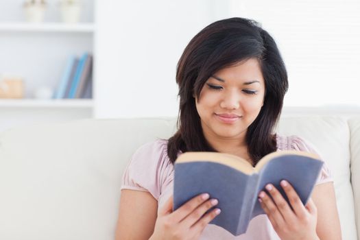 Woman sitting on a sofa while reading a book in a living room