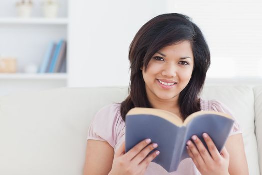 Woman sitting on a couch while holding a book in a living room