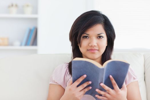 Woman sitting on a couch and holding a book in a living room