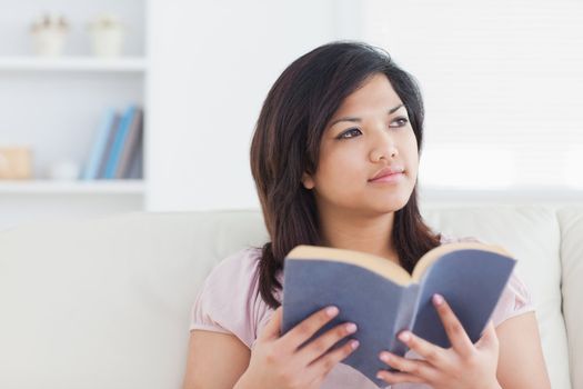 Woman sitting on a sofa while holding a book in a living room