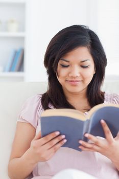Woman sits on a couch while reading a book in a living room