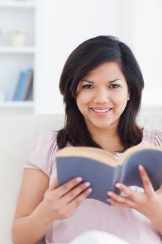 Woman sitting on a couch while she reads a book in a living room