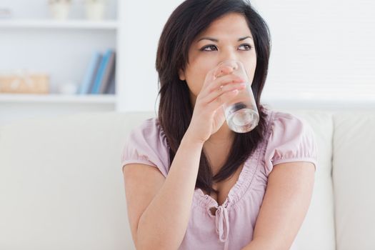 Woman drinking from a glass of water in a living room