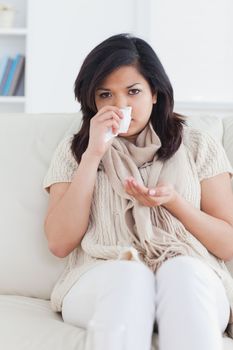Woman blowing her nose in a living room