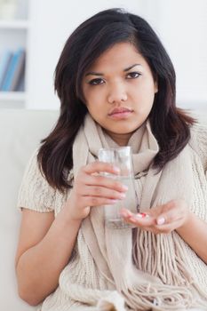 Sick woman taking pills in a living room