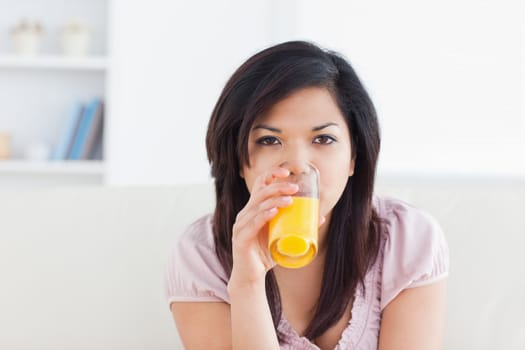 Woman drinking a glass of orange juice in a living room