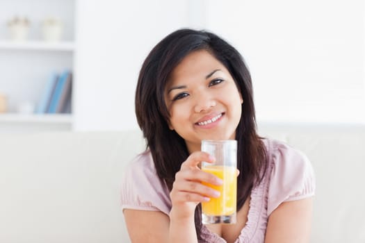 Smiling woman holding a glass of orange juice in a living room