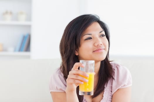 Woman smiling and holding a glass of orange juice in a living room