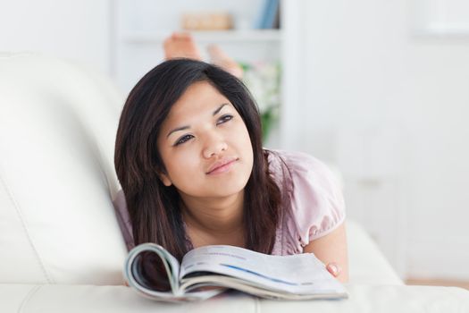 Woman lays on a sofa while reading a magazine in a living room