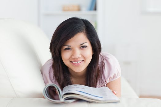 Woman resting on a sofa while holding a magazine in a living room