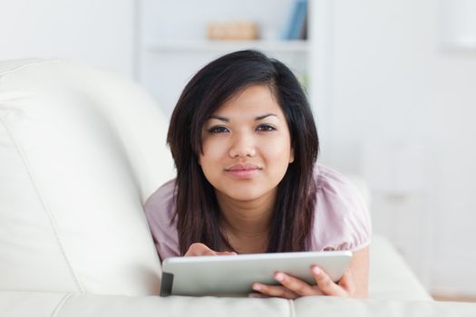 Woman typing on a tablet while resting on a couch in a living room