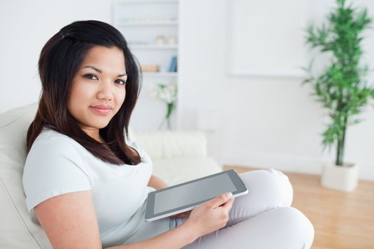 Woman sitting on a sofa while holding a tactile tablet in a living room