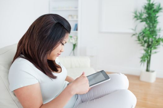 Woman sitting on a sofa while holding and playing with a tactile tablet in a living room