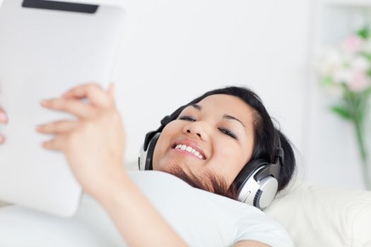 Woman lying on a couch with headphones on and a tactile tablet in her hands in a living room