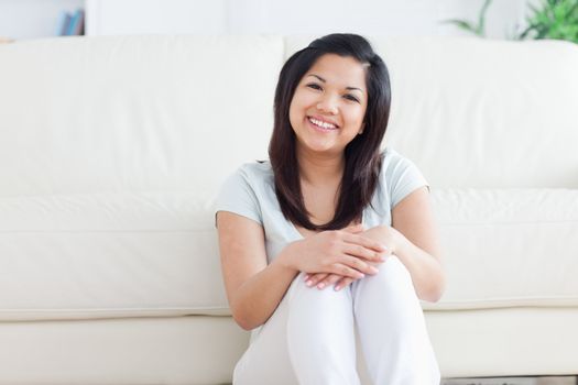 Woman smiles as she sits on the floor in a living room in a living room