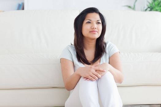 Woman smiling as she sits on the floor in front of a couch in a living room