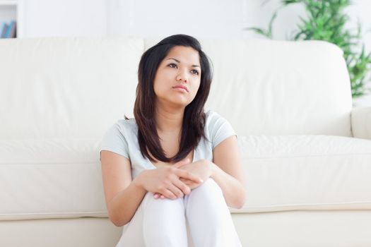 Woman is sitting in front of a couch in a living room